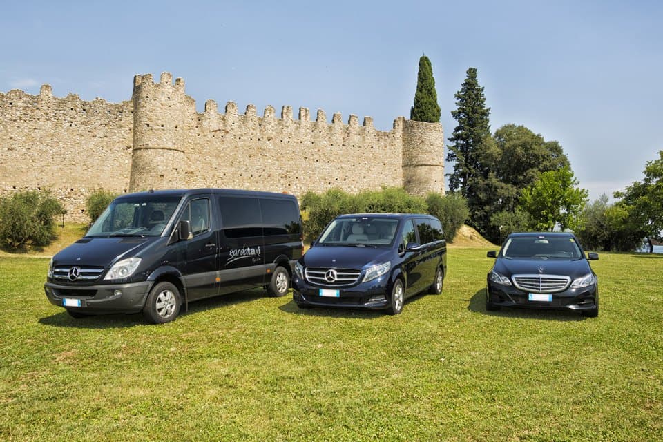 La flotta GardaTaxi, Mercedes Sprinter, Classe V e Classe E, davanti alle mura di un castello sul Lago di Garda