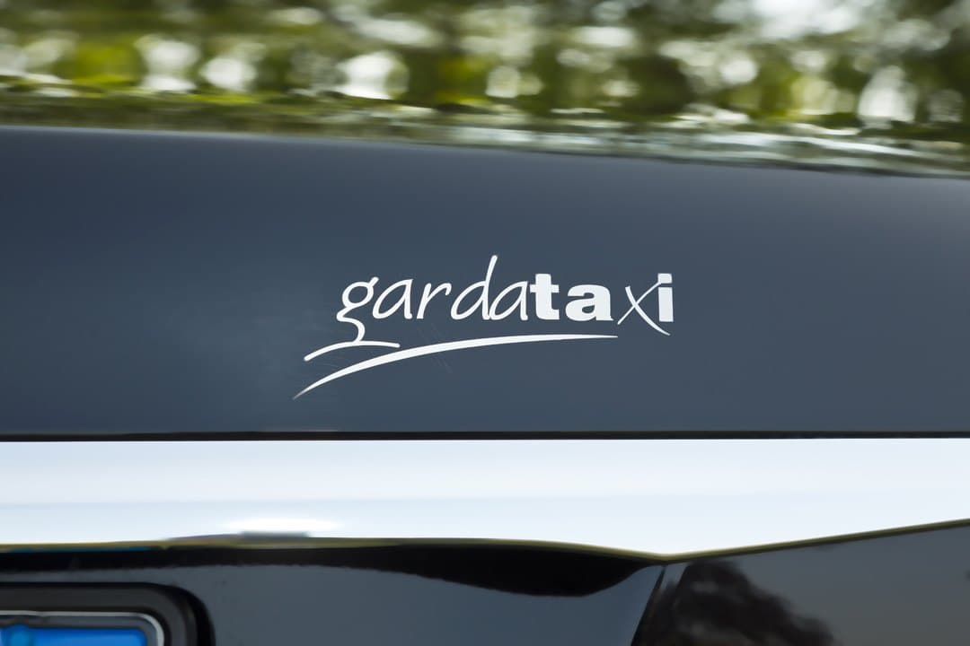 Il logo GardaTaxi sulla carrozzeria nera di una Mercedes Classe E